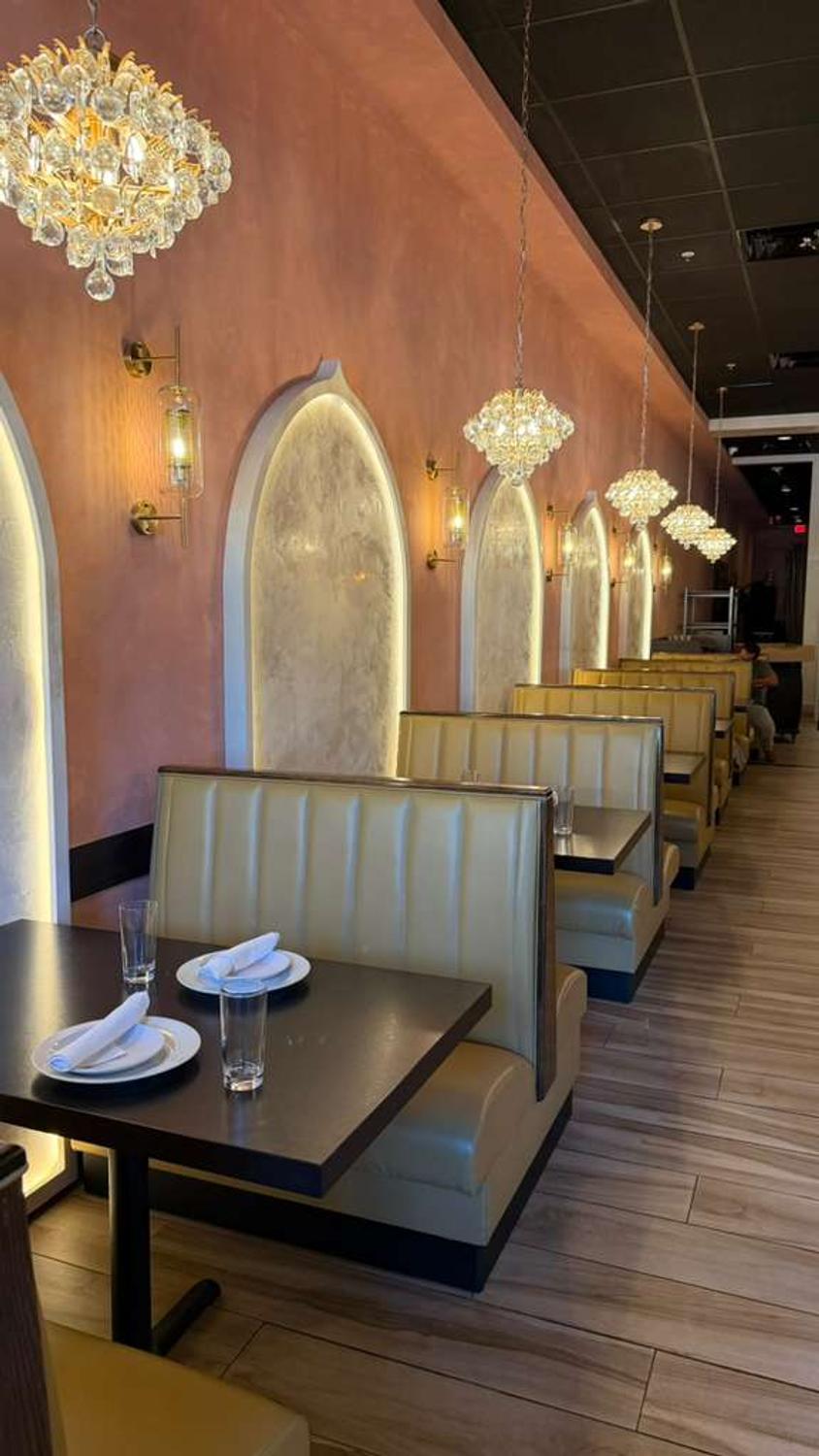 Booth seating beneath crystal chandeliers at Bombay Grove